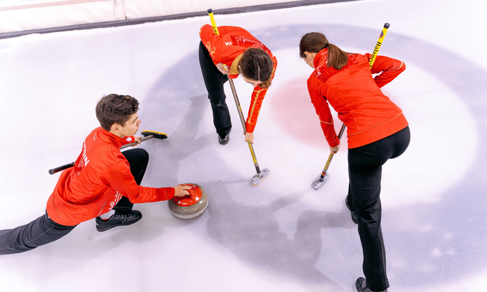 Zawodnicy curlingu podczas rzutu kamieniem na lodowisku